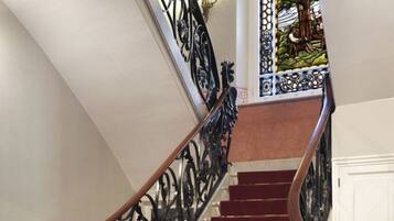 Una escalera con alfombra roja y barandilla de hierro forjado negro.