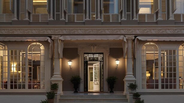 Un edificio imponente con fachada simétrica, amplias ventanas en arco y una entrada central con puerta decorativa.