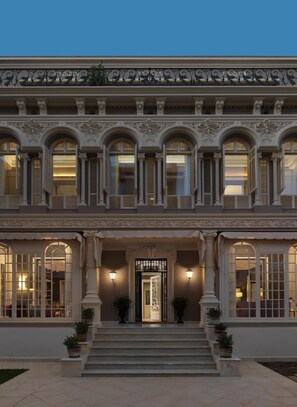 Un edificio imponente con fachada simétrica, amplias ventanas en arco y una entrada central con puerta decorativa.