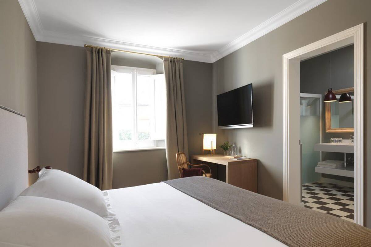 Une chambre d’hôtel équipée d’un lit, d’un bureau, d’une télévision et d’une armoire.