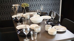 A dining table set with plates, bowls, cups, and wine glasses, with a patterned wall in the background. - Sesoko  Villa (Motobu)