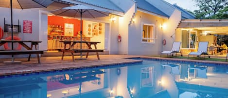 Una piscina al aire libre, sombrillas, tumbonas