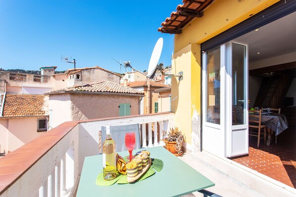 A balcony with a table set for dining, a satellite dish, and a sliding glass door leading to an outdoor dining area. - LE BELVEDERE AP1059 by RIVIERA HOLIDAY HOMES (Villefranche-sur-Mer)
