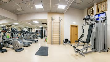Un gimnasio con cintas de correr, bicicletas estáticas y máquinas de pesas.