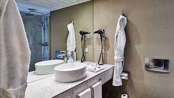 Un baño moderno con dos lavamanos, un secador de pelo y un tendedero para toallas.