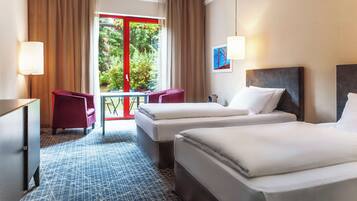 A hotel room with two beds, a desk, a chair, and a window with curtains.