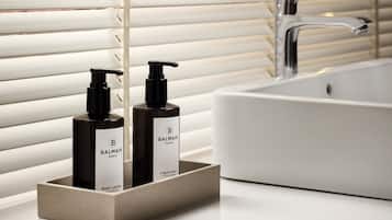A bathroom with a white sink, two bottles of Balmain body lotion, and a modern faucet.