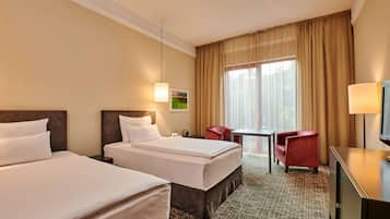 A hotel room with two beds, a desk, a chair, and a television.