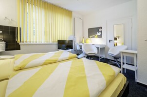 Una habitación de hotel con cama, escritorio, silla, televisor y baño.