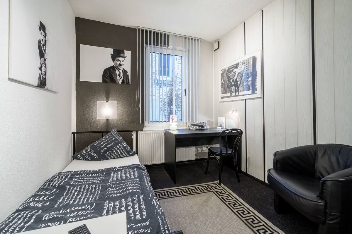 A bedroom with a bed, a desk, a chair, and a leather sofa.