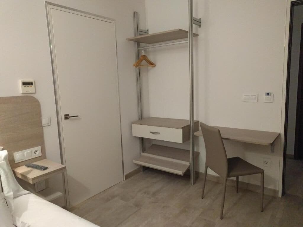 A compact room with a bed, a desk, a chair, and a wardrobe.