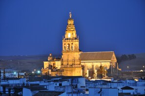 A historic building with a prominent tower and a large facade, surrounded by residential buildings. - Patios del Orfebre (Córdoba)