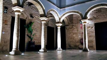 Un interior espacioso con altos arcos de piedra, columnas y una planta en maceta.