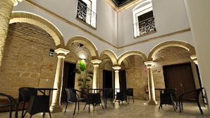 A spacious courtyard with stone arches, a potted plant, and outdoor seating. - Patios del Orfebre (Córdoba)
