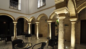 An interior courtyard with stone arches, tables, and chairs. - Patios del Orfebre (Córdoba)