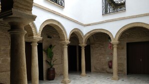 A courtyard with stone columns, arches, and a tiled floor. - Patios del Orfebre (Córdoba)