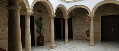 A courtyard with stone columns, arches, and a tiled floor.