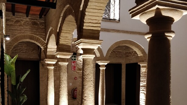 An interior with stone columns, a tiled floor, and a potted plant. - Patios del Orfebre (Córdoba)