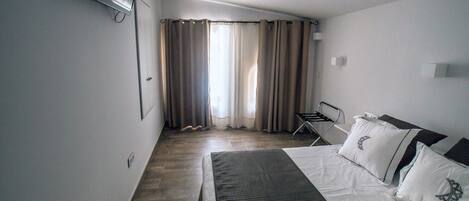 A hotel room with a bed, a chair, and a window with curtains.