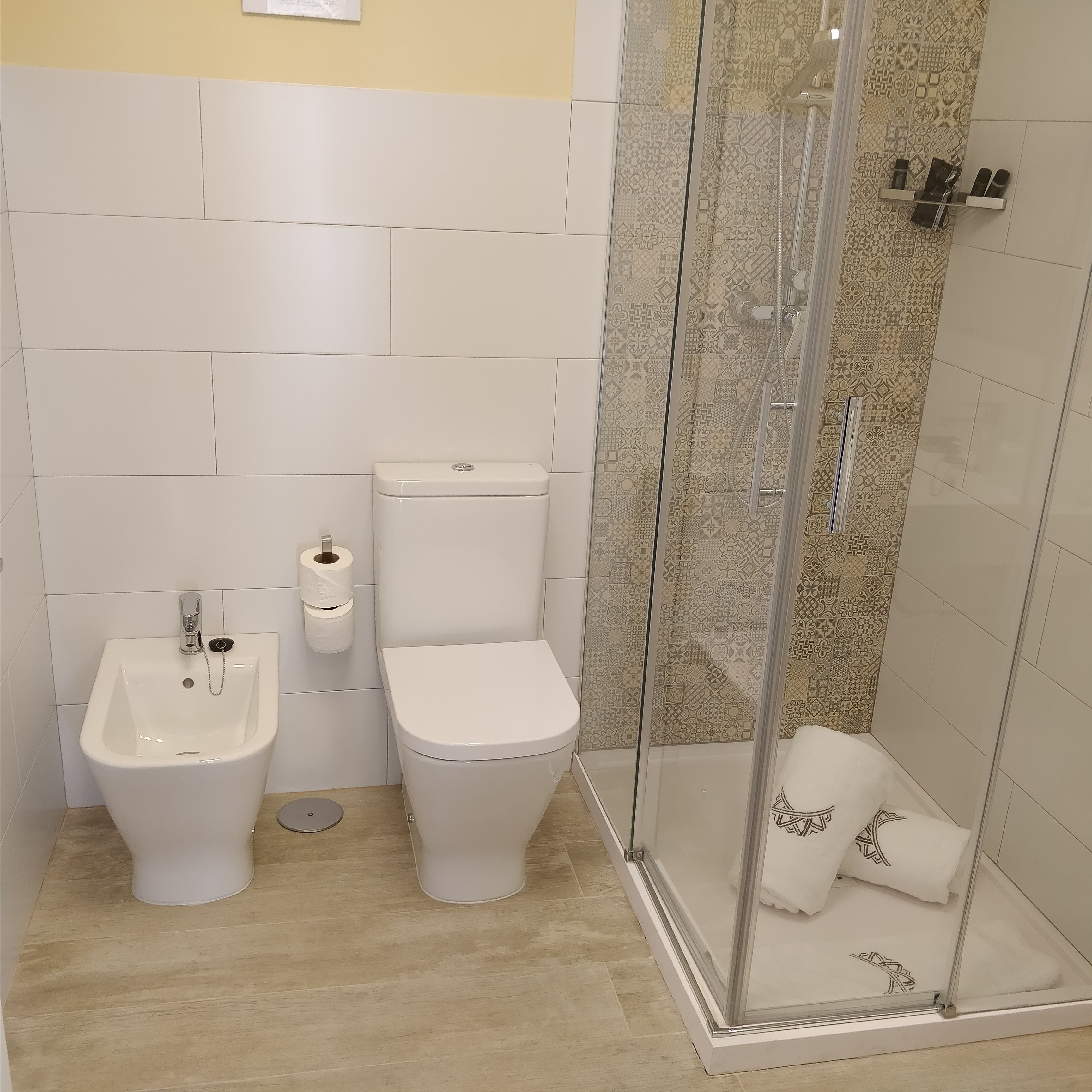 Ein modernes Badezimmer mit integriertem Bidet, Toilette und Duschkabine.