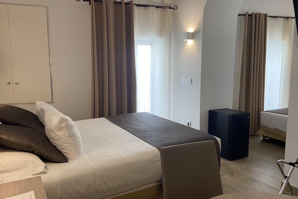 A hotel room with a bed, a desk, a chair, and a wardrobe.