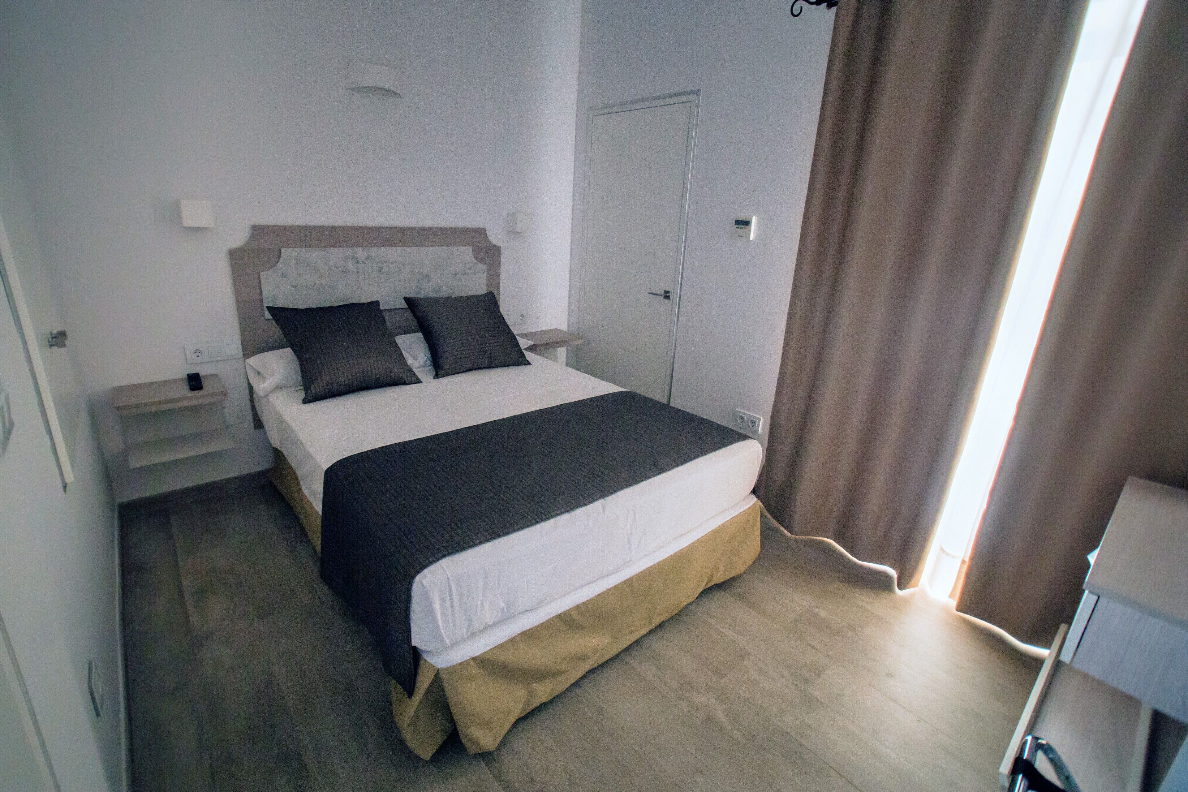 Ein Schlafzimmer mit Bett, Nachttischen und einer Tür.