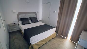 Un dormitorio con cama, mesitas de noche y una puerta.