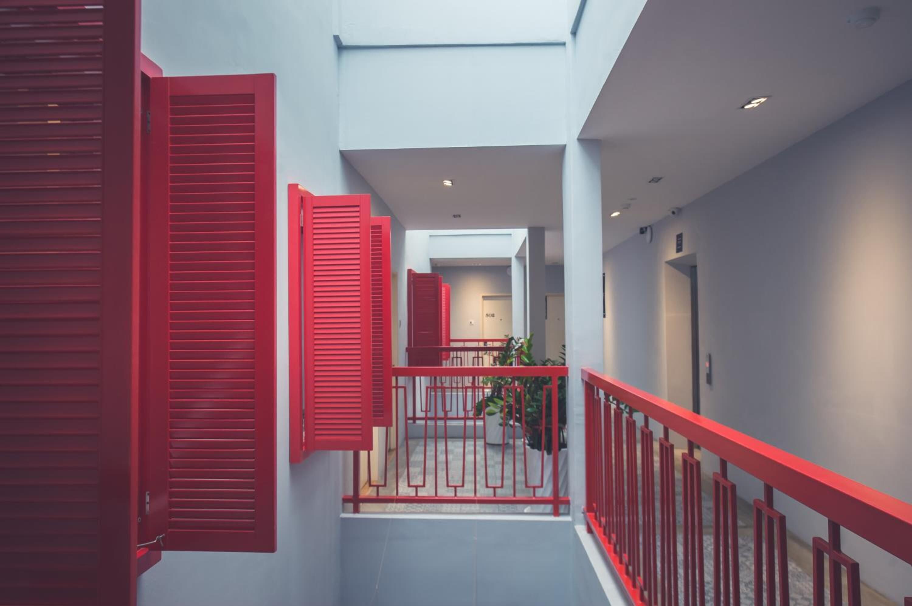 A corridor with red railings and doors, leading to a staircase.