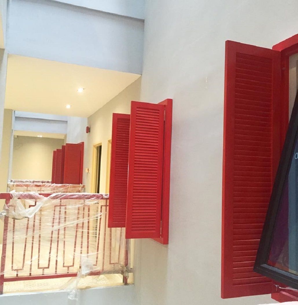 A room with red shutters, a window, and a staircase leading to another area.