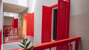 Una escalera con barandillas y contraventanas rojas, que conduce a un espacio interior.