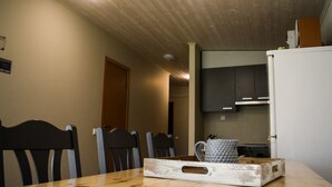 A dining area with a wooden table and chairs, a kitchen in the background, and a sign on the wall. - Karjamaa Camping (Parnu)