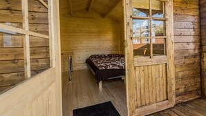 A wooden cabin interior with a bed, a window, and a door. - Karjamaa Camping (Parnu)