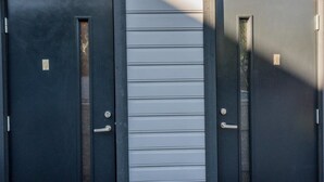Two dark-colored doors with handles, a vertical window, and a horizontal window. - Karjamaa Camping (Parnu)