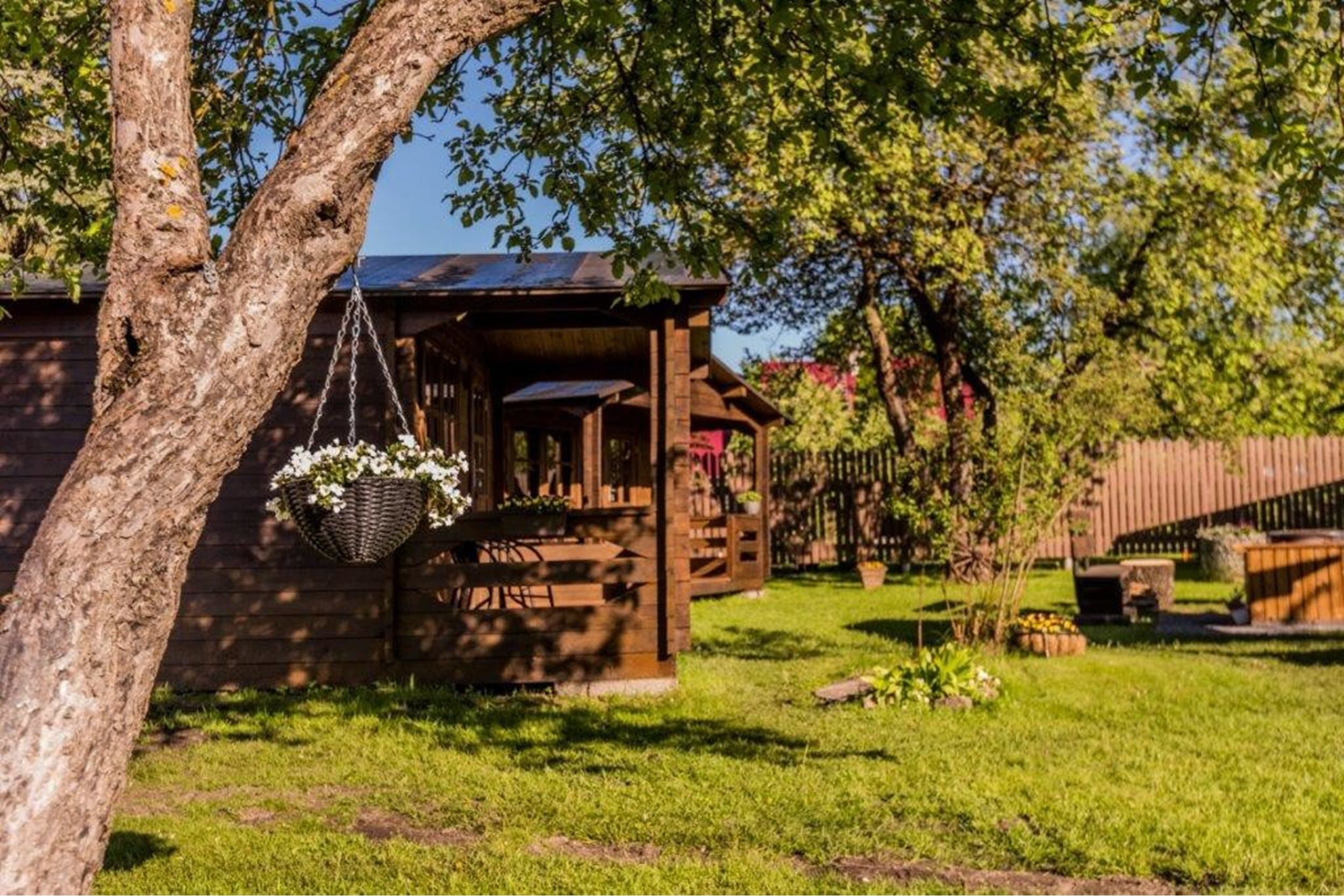 Un rustico cottage in legno con veranda, immerso nel verde e circondato da alberi.