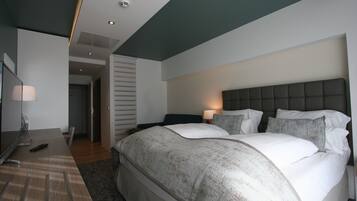 Una habitación de hotel moderna con una cama grande, mesitas de noche, un escritorio y un televisor.