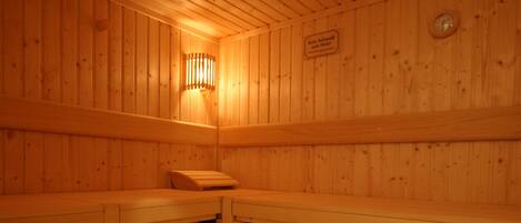 Una sauna de madera con bancos y un aplique en la pared.