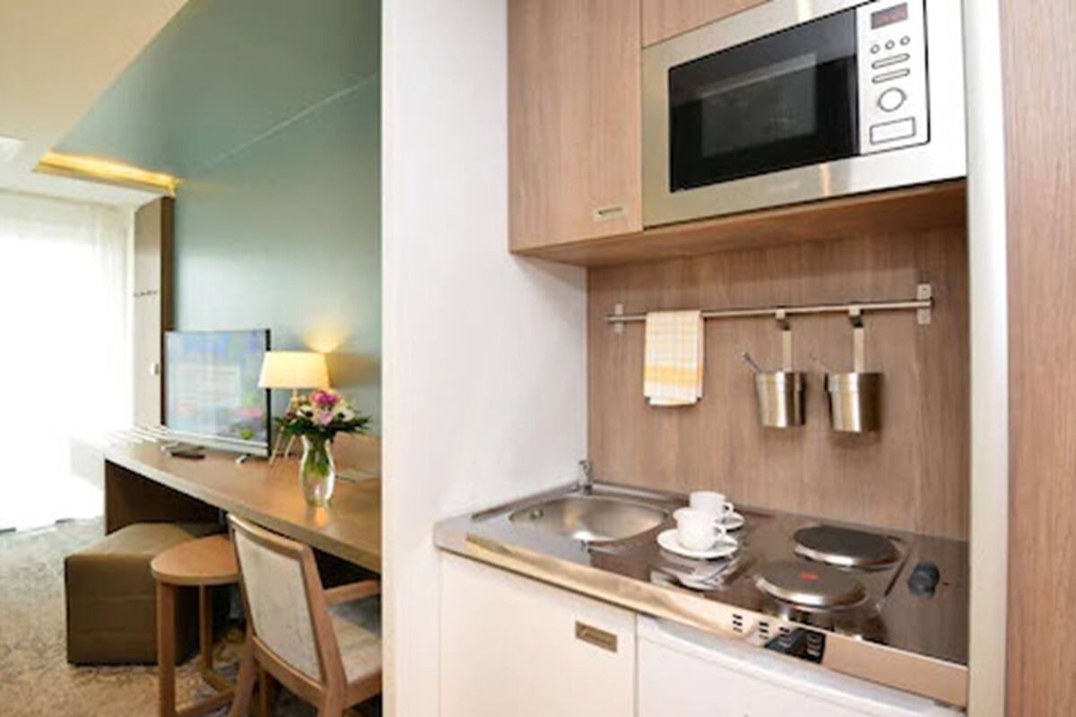 A compact kitchenette with a microwave, stove, and sink.