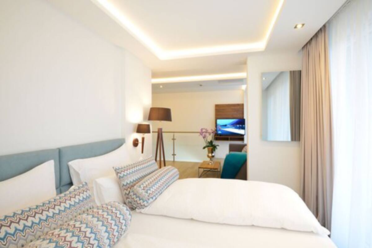 A modern hotel room with a large bed, a desk, and a TV.
