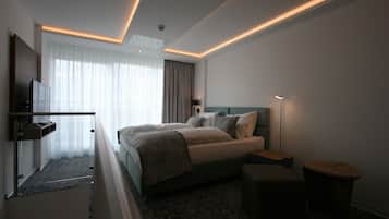 A modern hotel room with a large bed, bedside tables, a desk, and a TV.
