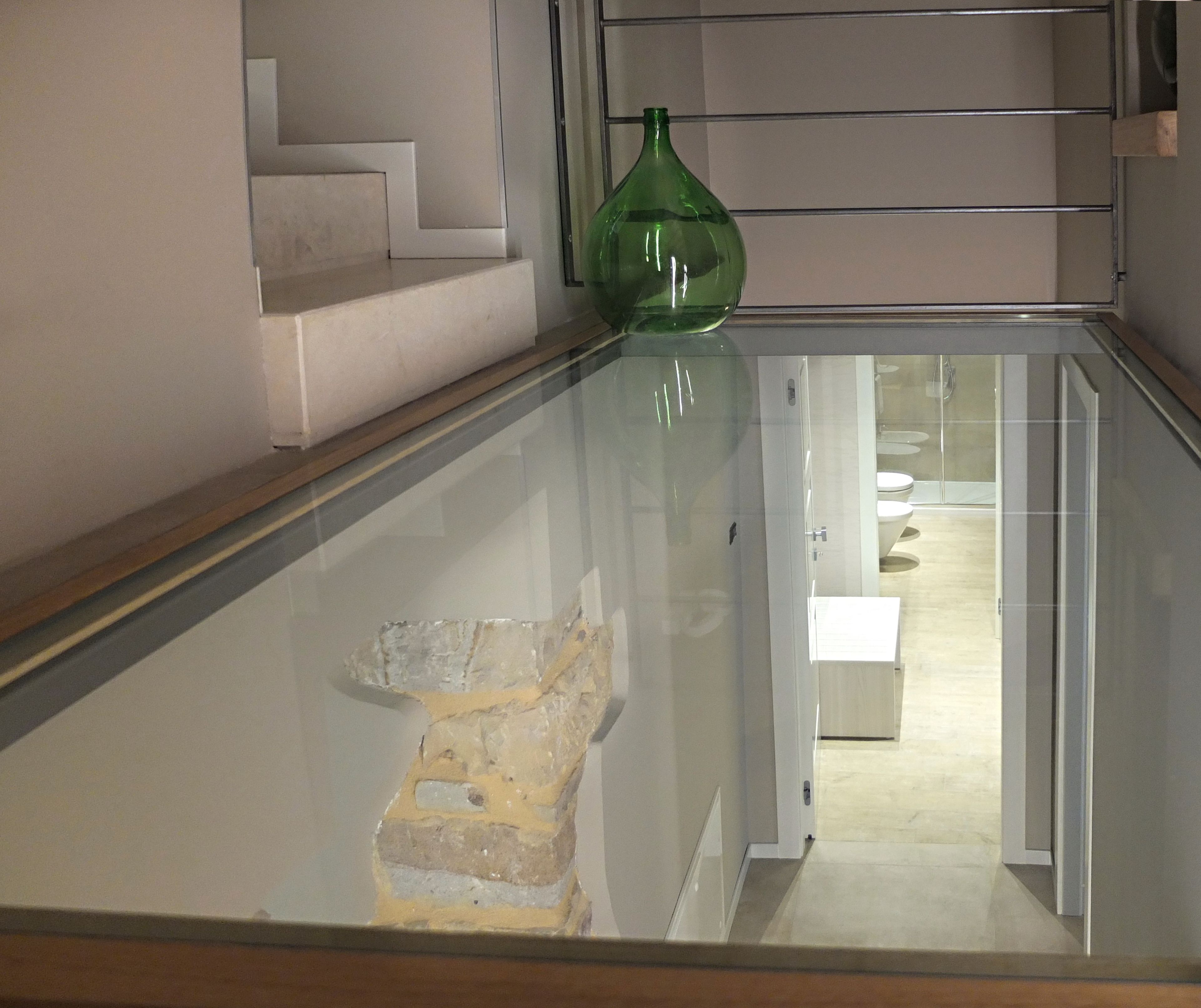 A glass-walled staircase leading to a bathroom with a shower and toilet.