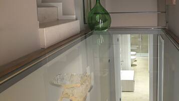 A glass-walled staircase leading to a bathroom with a shower and toilet.