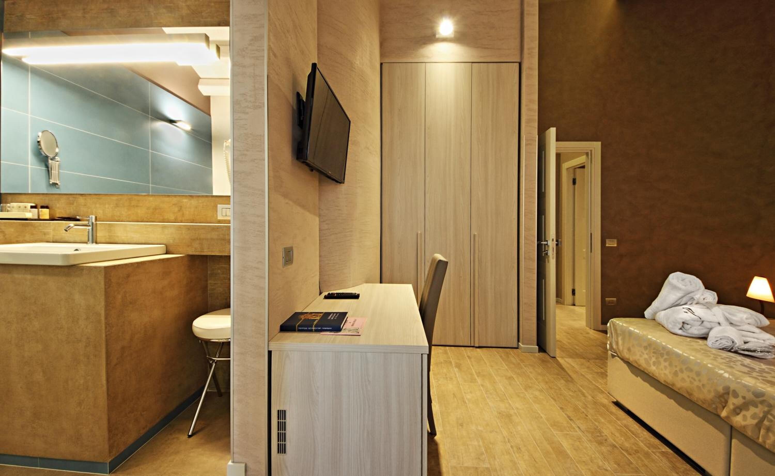 A modern hotel room with a bathroom, a desk, and a bed.