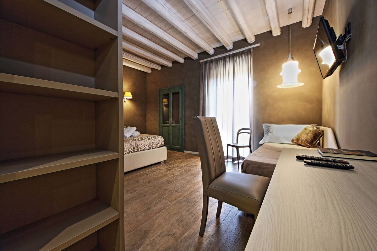 A bedroom with a bed, a chair, a desk, and a shelf.