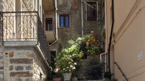 A narrow stone staircase leading up to a building with multiple balconies, surrounded by potted plants and flowers. - Notti O'Tunn (Geraci Siculo)