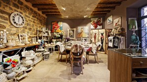 A rustic interior with stone walls, wooden beams, and various home decor items displayed on shelves and tables. - Notti O'Tunn (Geraci Siculo)