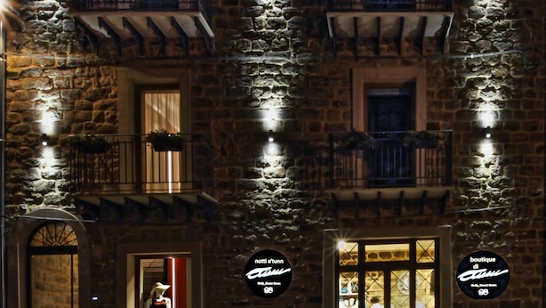 A stone building with two ground-floor entrances, each with a sign indicating a boutique hotel. - Notti O'Tunn (Geraci Siculo)