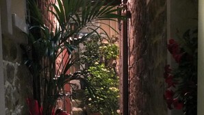 A narrow stone-paved alleyway with potted plants on either side. - Notti O'Tunn (Geraci Siculo)