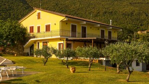 A two-story yellow building with a balcony, surrounded by a well-maintained lawn and trees. - L' Aia Resort (Trentinara)