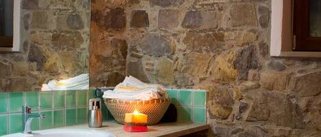 Ein Badezimmer mit Steinwand, Waschbecken, Spiegel und zwei Pissoirs.