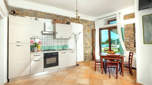 A modern kitchen with white cabinets, a gas stove, and a dining area with a table and chairs. - L' Aia Resort (Trentinara)